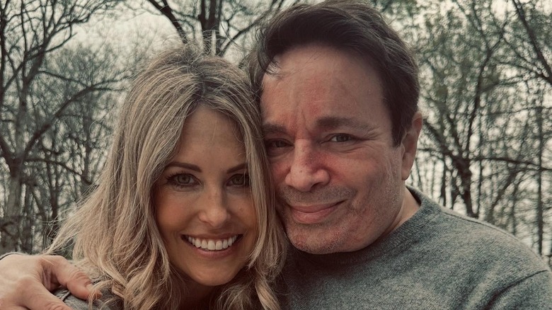 Actor Chris Kattan smiling with his arm around his wife in a selfie outside