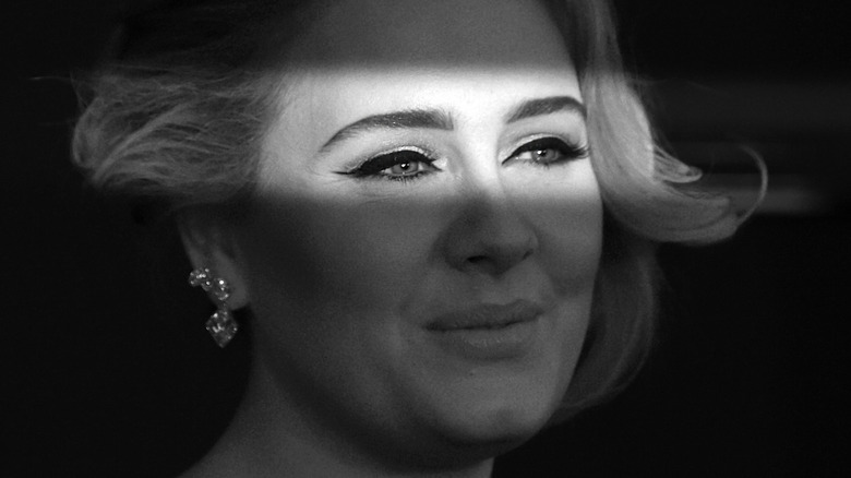 A dramatic black and white photo of Adele grinning