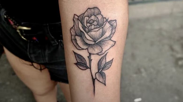 Black rose tattoo on forearm