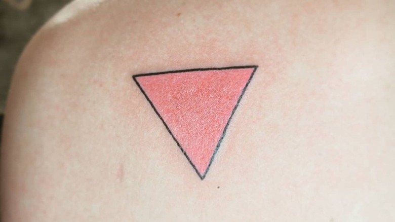 Ein Mann zeigt sein pinkfarbenes Dreieckstattoo
