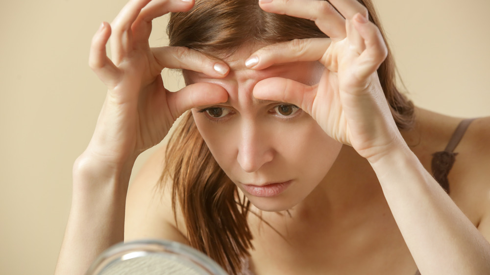 Woman checking skin in mirror