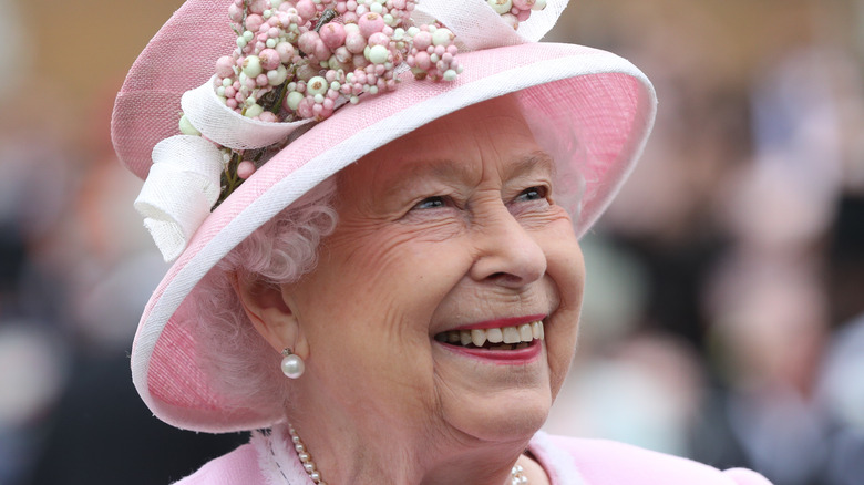Queen Elizabeth smiling in a pink hat