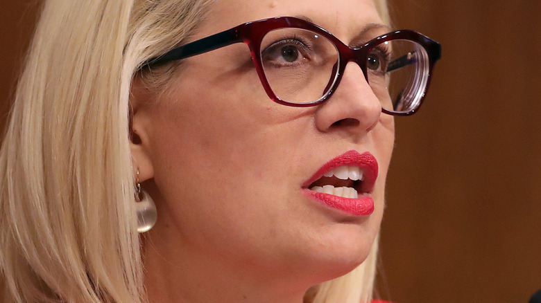 Kyrsten Sinema speaks in the Senate with glasses and red lipstick