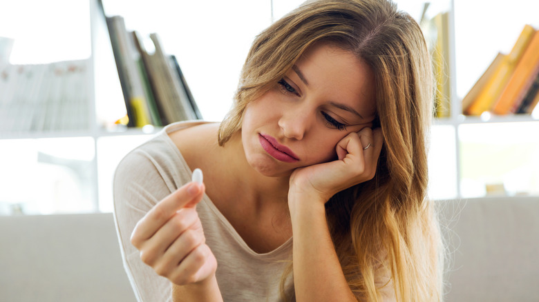 Sad-looking woman looking at pill