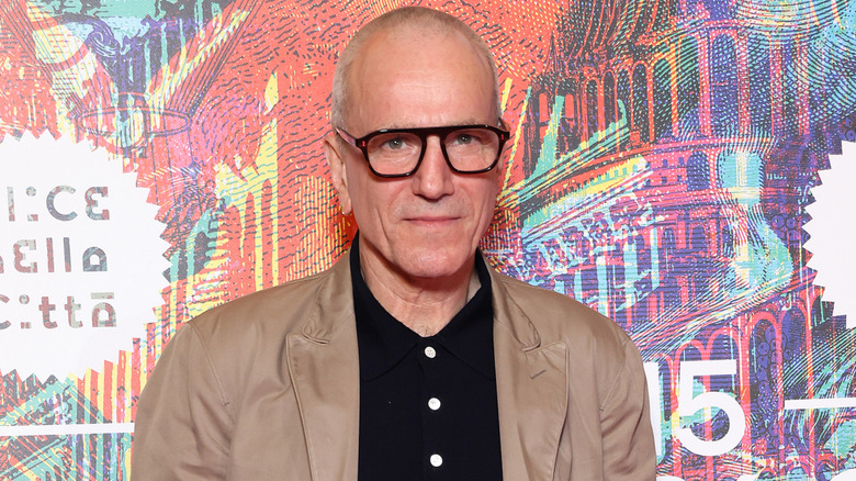 Daniel Day-Lewis posing on the red carpet in glasses, a beige jacket, and a black shirt