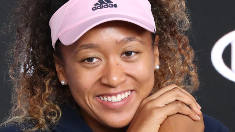 Naomi Osaka smiling in pink visor