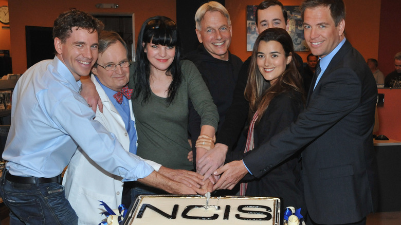 The stars of NCIS cutting a celebration cake for the show
