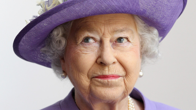 Queen Elizabeth II in an all-purple outfit with a mischievous twinkle in her eyes