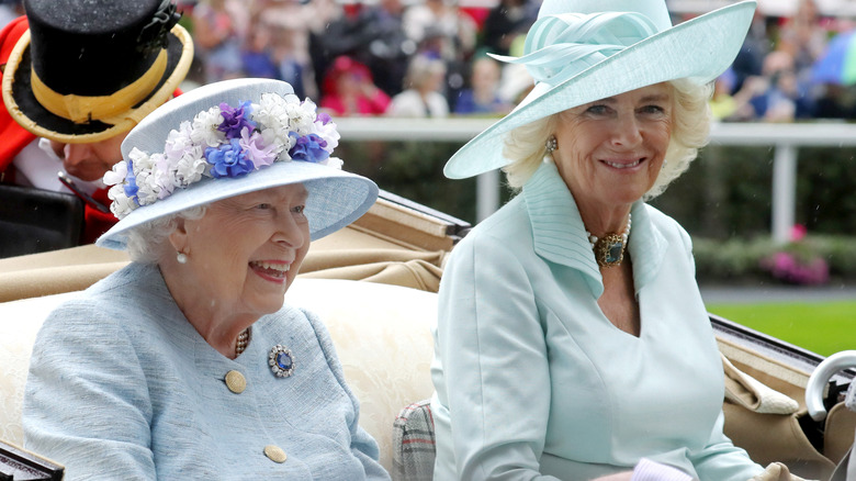 Queen Elizabeth Laughing next to a smiling Camilla, Queen Consort, as they ride together in a carriage