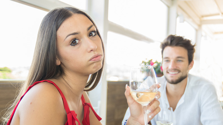 Woman drinking while listening to man