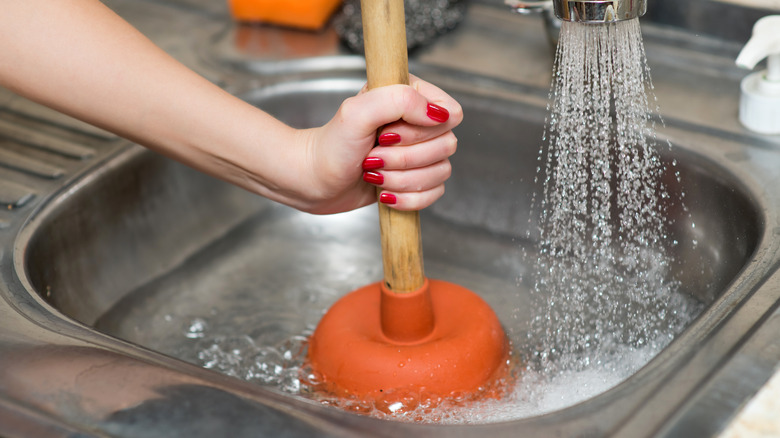 Woman trying to plunge clogged kitchen sink