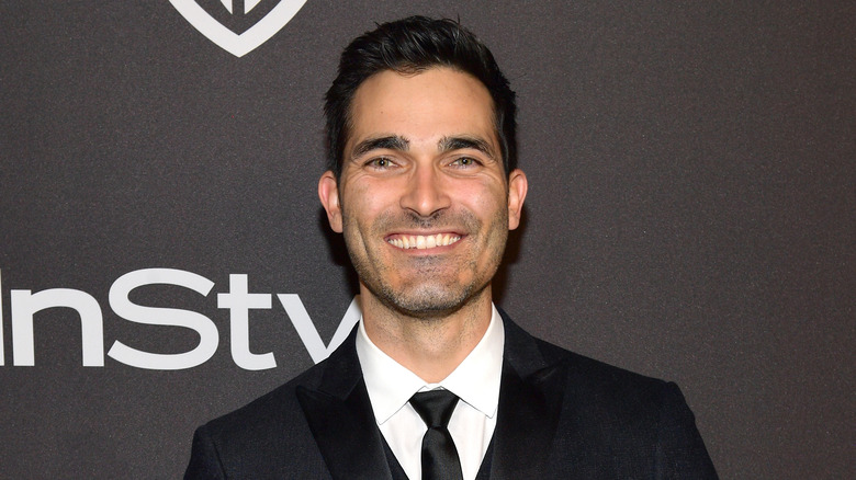 Tyler Hoechlin smiles while wearing a black suit and tie.