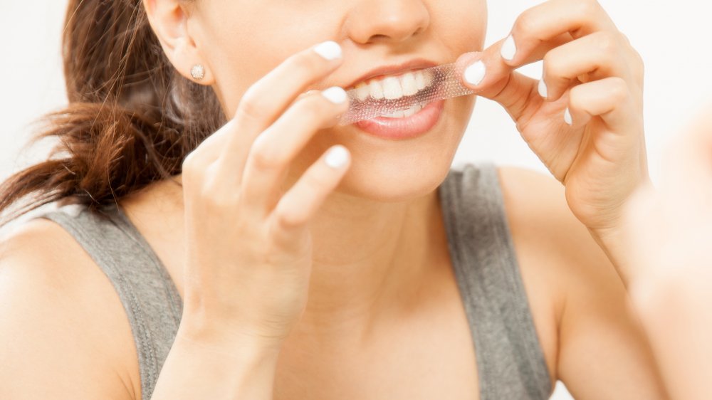 Woman applying a whitening strip