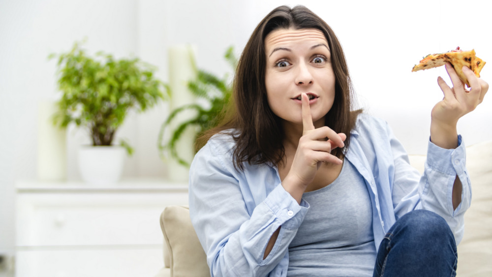 Woman sneaking slice of pizza