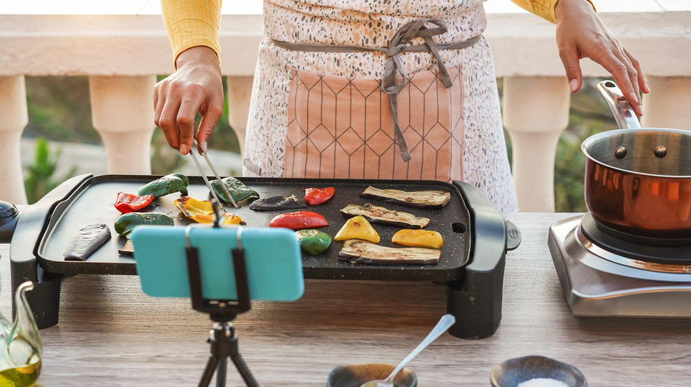 A female chef cooking with the help of a mobile recipe