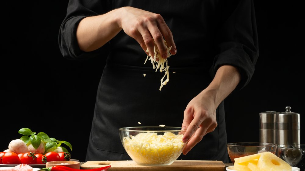 Chef adding shredded cheese to a bowl