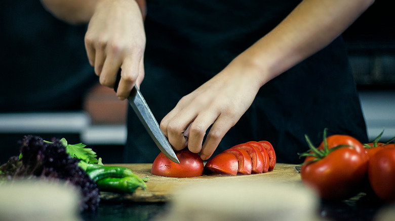 A person chops fresh vegetables with a kitchen knife