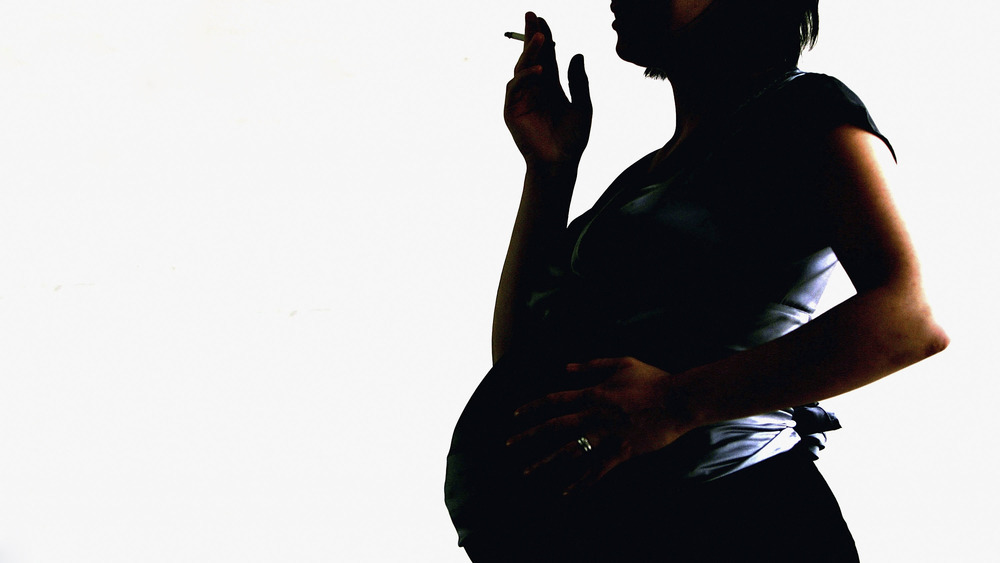 Silhouette of pregnant woman smoking