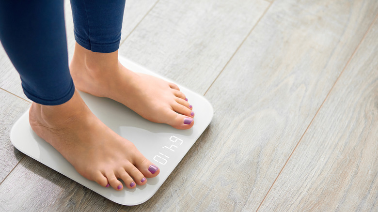 A woman weighing herself on a scale 