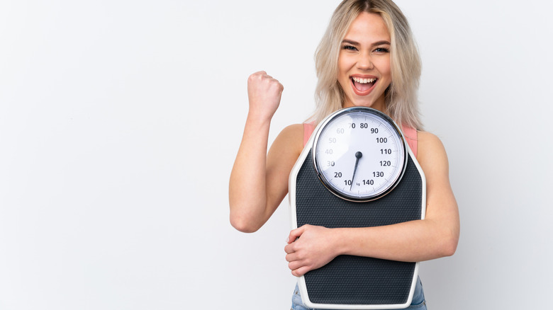 A happy woman holding the scale
