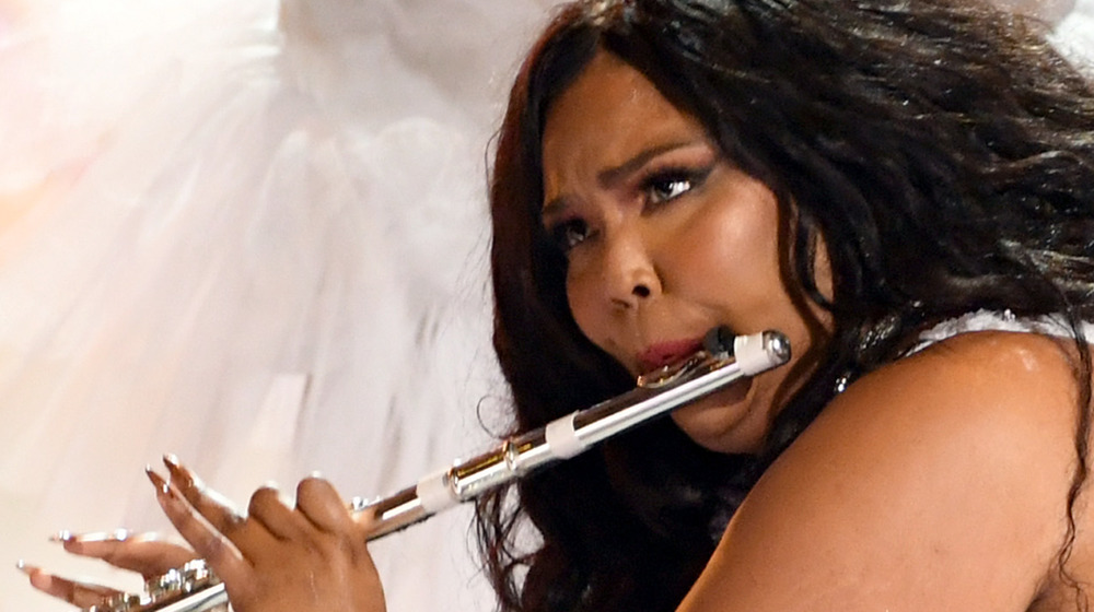 Lizzo performing onstage with her flute