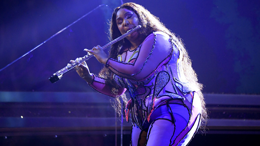 Lizzo performing onstage with her flute