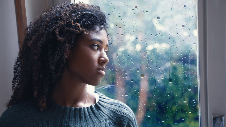 Young woman feeling said while watching the rain 