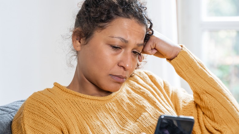 sad woman looking at phone