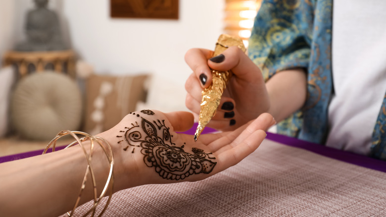 Professional applying henna ink to woman's hand