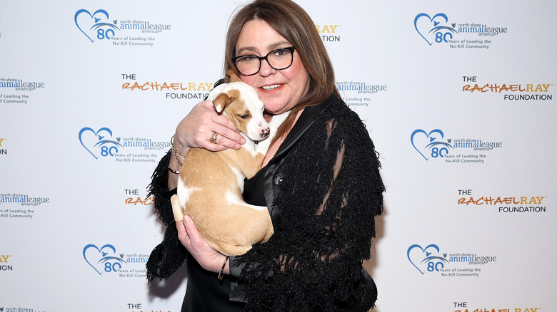 Rachael Ray cuddling a dog while wearing glasses