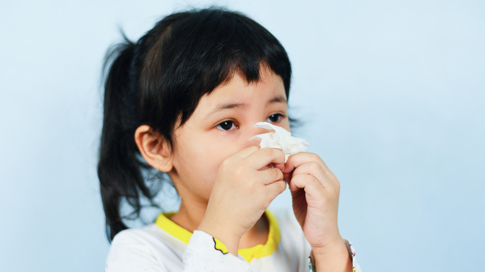 Young girl blowing her nose