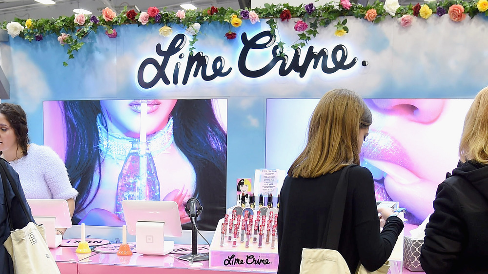 Lime Crime booth with customers checking out their products.