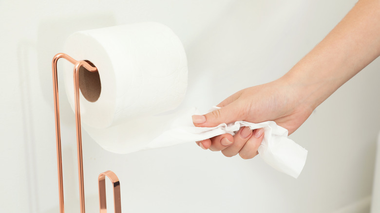 woman reaching for toilet paper
