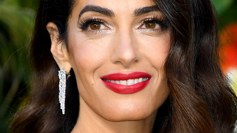 Amal Clooney smiling with red lipstick