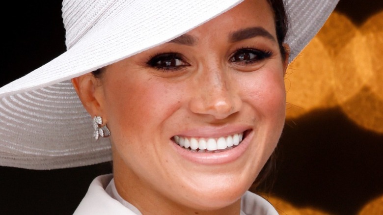 Meghan Markle smiling in a big white hat at the Jubilee
