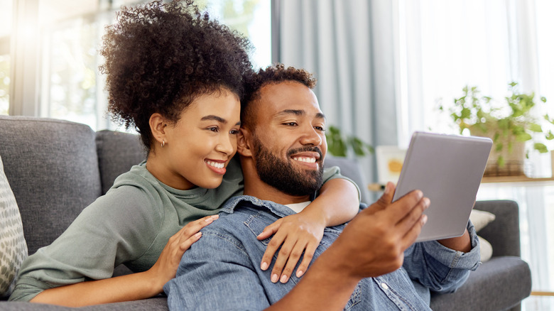 Couple embraces while looking at tablet