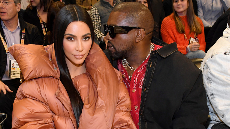 Kanye West stares at Kim Kardashian, who looks directly at the camera