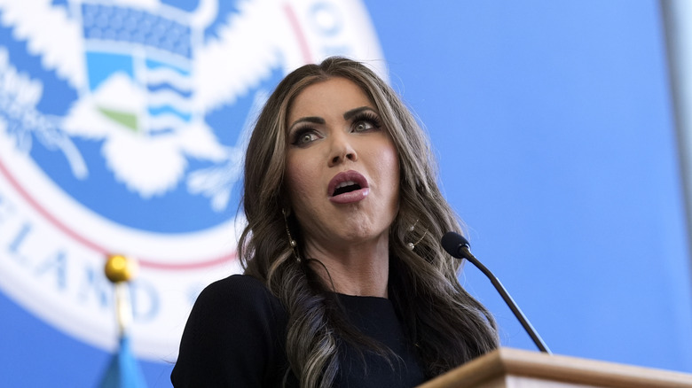 Kristi Noem speaking into a microphone addressing the Department of Homeland Security