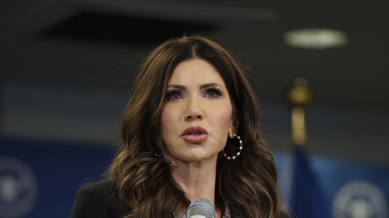 Kristi Noem standing in front of a microphone