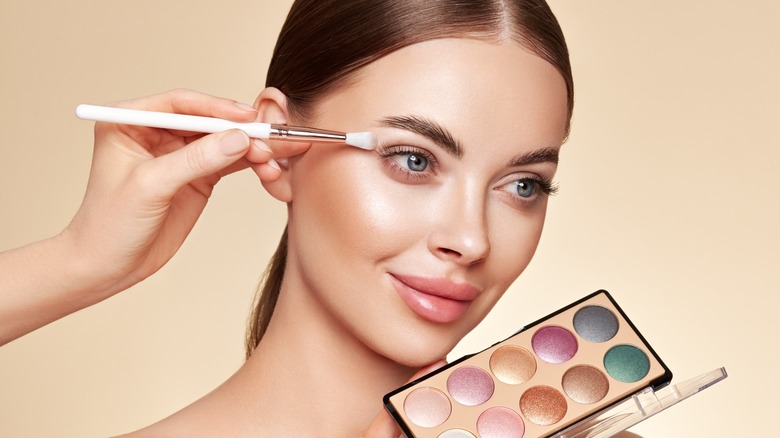 Makeup artist applying eyeshadow to woman