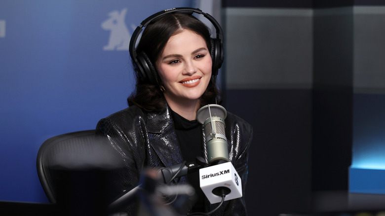 Selena Gomez giving a radio interview with a microphone and headphones
