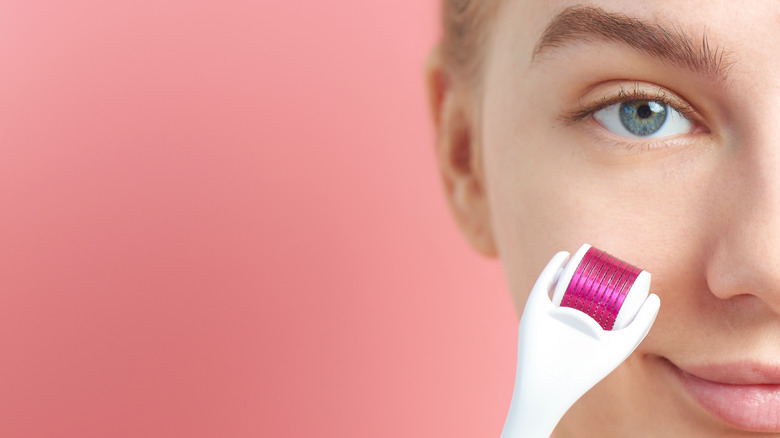 Woman holding a derma roller in front of her face