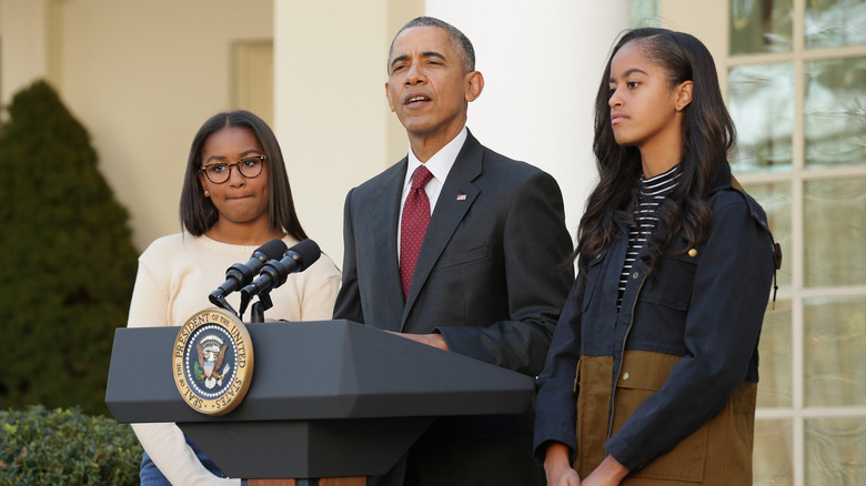 Sasha, Barack, and Malia Obama at a podium