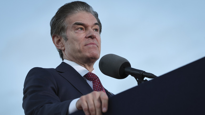 Dr. Oz standing at a podium looking grumpy in a dark suit
