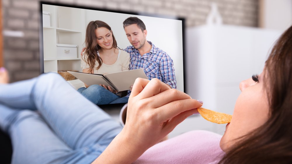 Woman watching TV with chips and soda