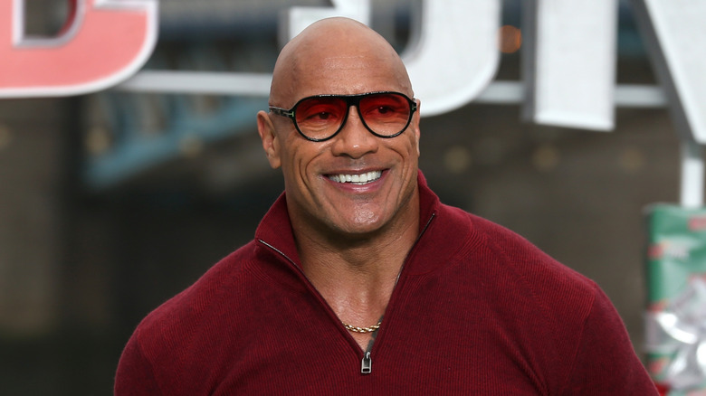 Dwayne Johnson attending photocall for 'Red One' while wearing a red shirt and sunglasses.