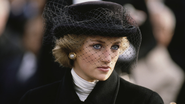 Princess Diana dressed in black with a lace veil and pearl earraings.
