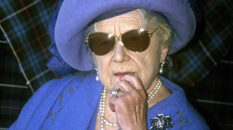 The Queen Mother looking pensive while wearing sunglasses.
