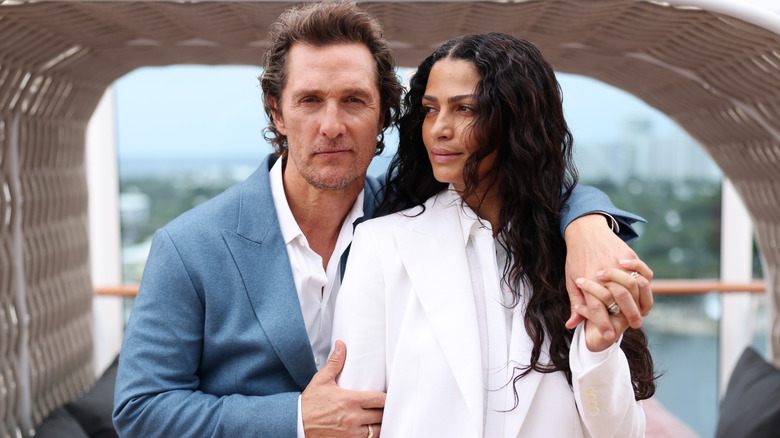 Matthew McConaughey holding Camila Alves while they hold hands