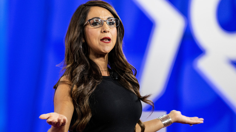 Lauren Boebert shrugging in a sleeveless black dress and glasses